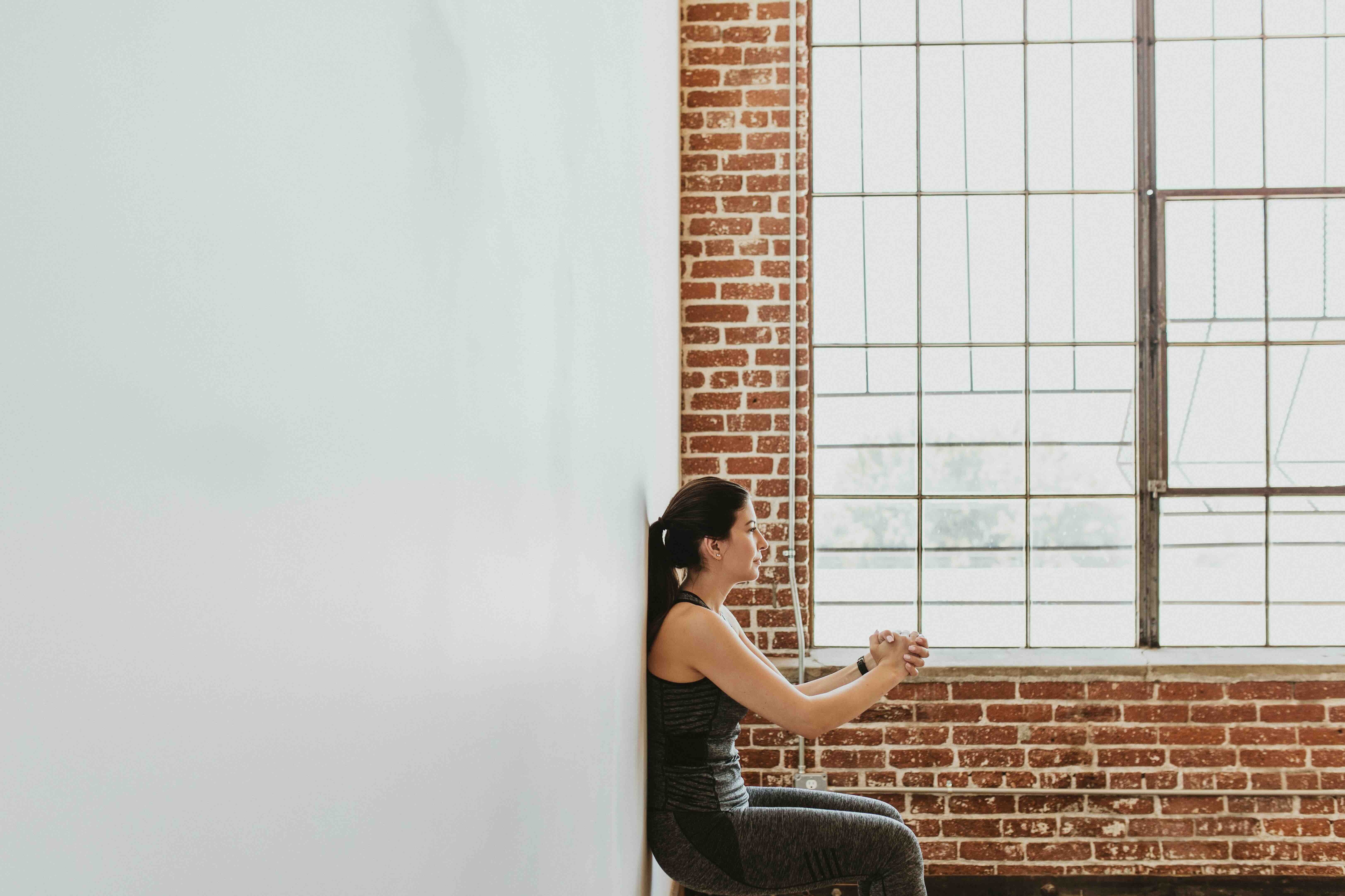 Sporty woman doing the chair against a wall