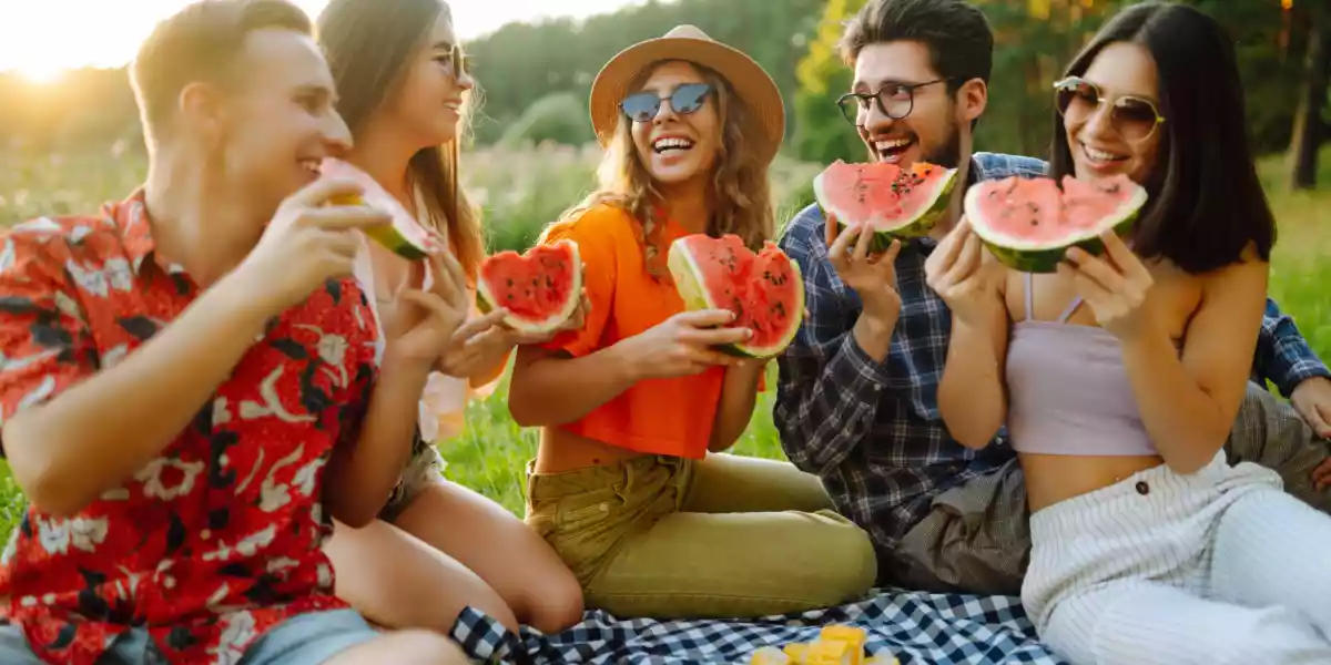 Group of friends eating fruits and natural foods in the open air